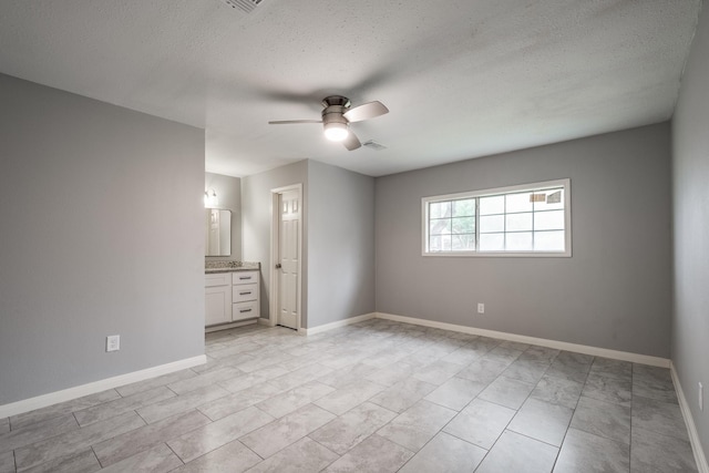 unfurnished bedroom featuring a textured ceiling, ensuite bathroom, and ceiling fan