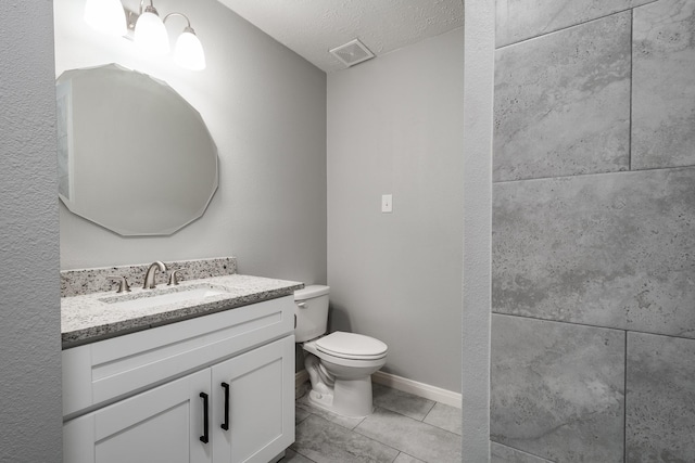 bathroom featuring tile patterned flooring, vanity, toilet, and a textured ceiling