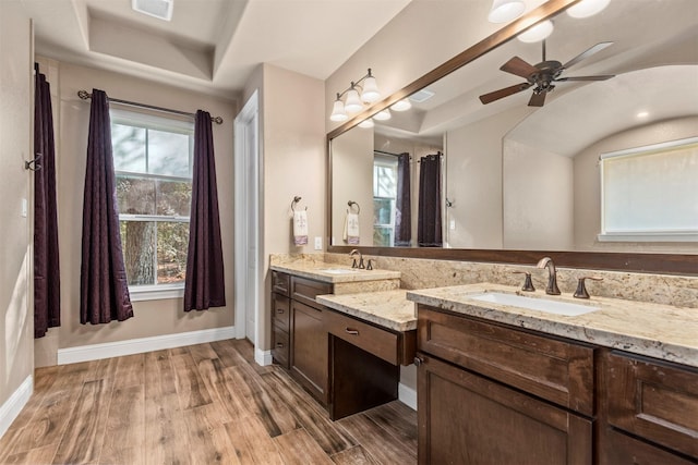 full bathroom featuring baseboards, ceiling fan, a tray ceiling, wood finished floors, and vanity