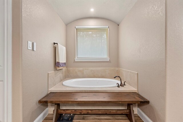 bathroom featuring baseboards, a garden tub, and a textured wall