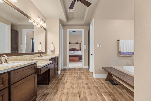 full bathroom with ensuite bathroom, a raised ceiling, ceiling fan, and wood finished floors