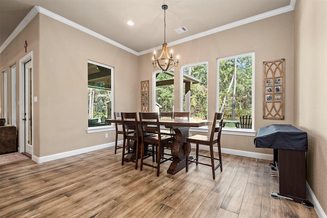 dining area with visible vents, wood finished floors, an inviting chandelier, crown molding, and baseboards