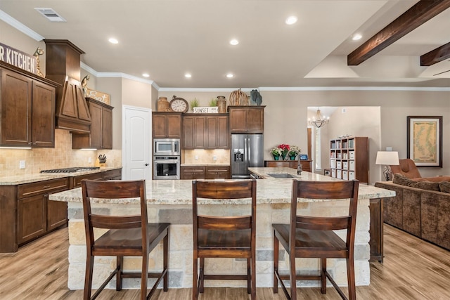 kitchen featuring visible vents, decorative backsplash, a large island, light wood-style floors, and appliances with stainless steel finishes