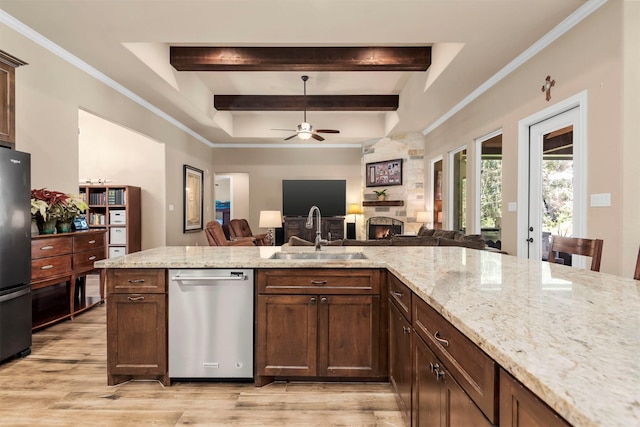 kitchen with beam ceiling, a sink, open floor plan, a stone fireplace, and dishwasher