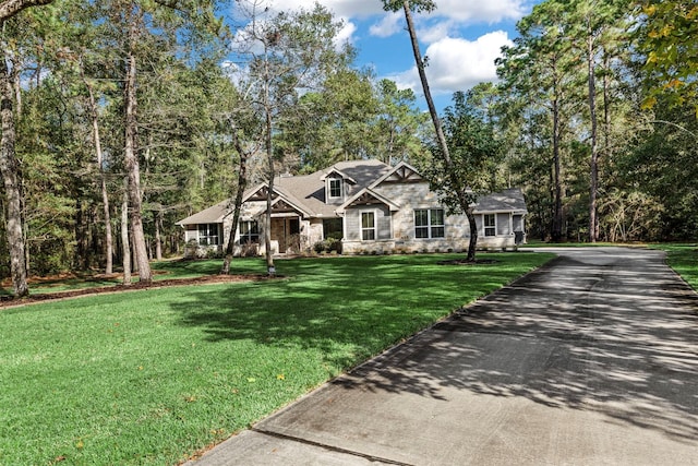 view of front facade with stone siding, driveway, and a front yard