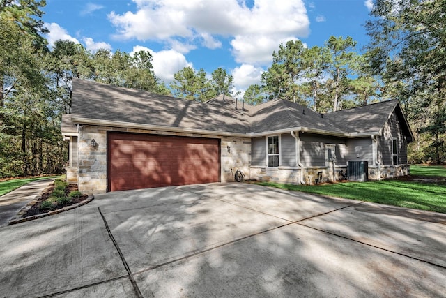 view of front of home with a front lawn, central air condition unit, driveway, stone siding, and an attached garage