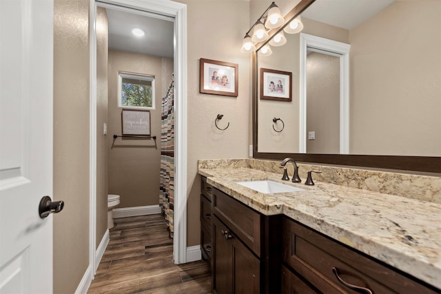 bathroom featuring vanity, toilet, wood finished floors, and baseboards