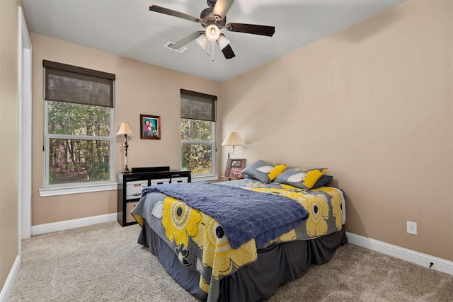 carpeted bedroom with visible vents, baseboards, and a ceiling fan