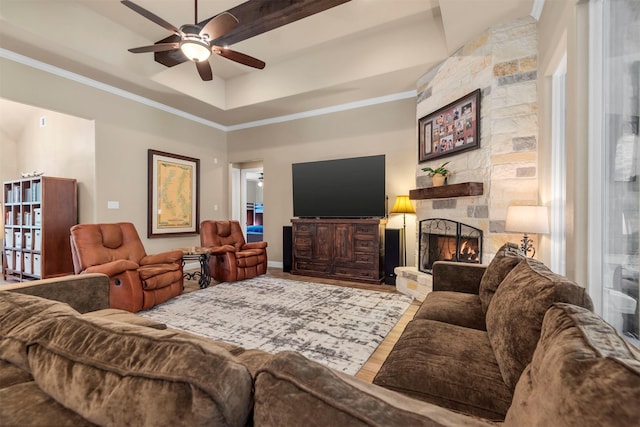 living area with a tray ceiling, ornamental molding, a fireplace, wood finished floors, and a ceiling fan