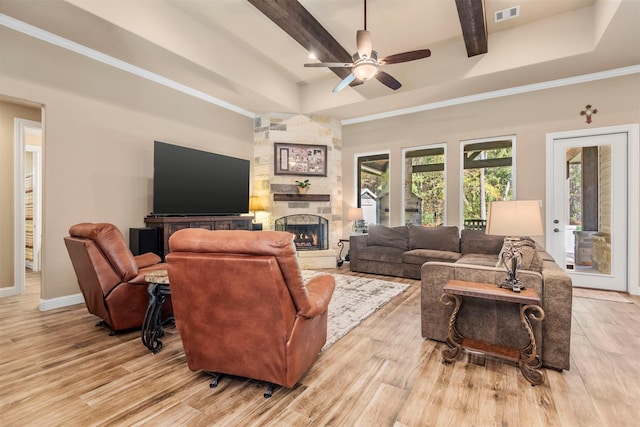 living area featuring visible vents, a stone fireplace, light wood-type flooring, and a tray ceiling