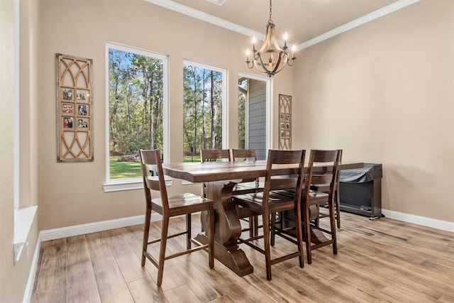 dining space featuring crown molding, light wood-style flooring, a notable chandelier, and baseboards