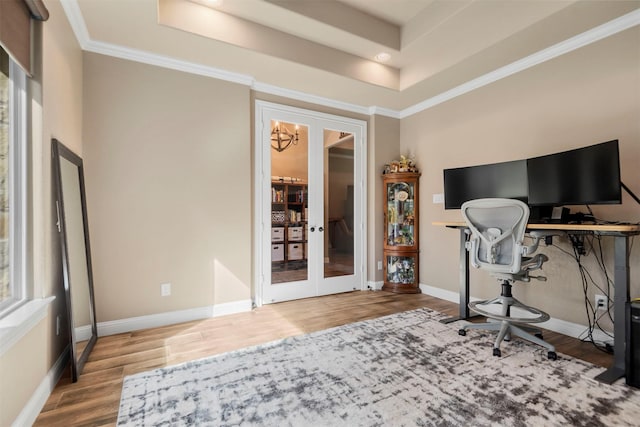 office space featuring baseboards, crown molding, a tray ceiling, and wood finished floors