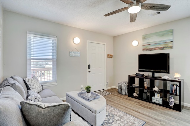 living room featuring a textured ceiling, light hardwood / wood-style flooring, and ceiling fan