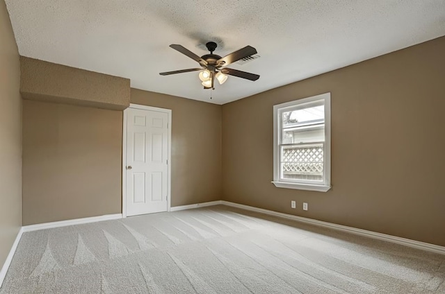 empty room with a textured ceiling, light colored carpet, and ceiling fan