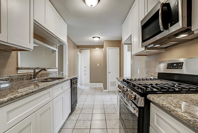 kitchen with white cabinets, sink, light stone countertops, light tile patterned floors, and appliances with stainless steel finishes