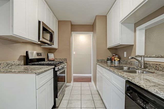 kitchen with sink, stainless steel appliances, light tile patterned floors, light stone counters, and white cabinets