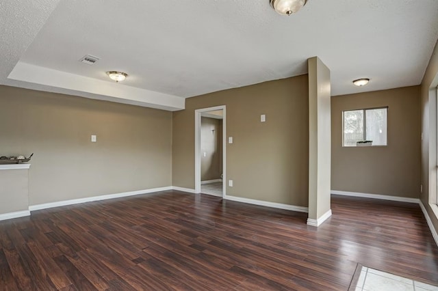 unfurnished room with a textured ceiling and dark hardwood / wood-style floors