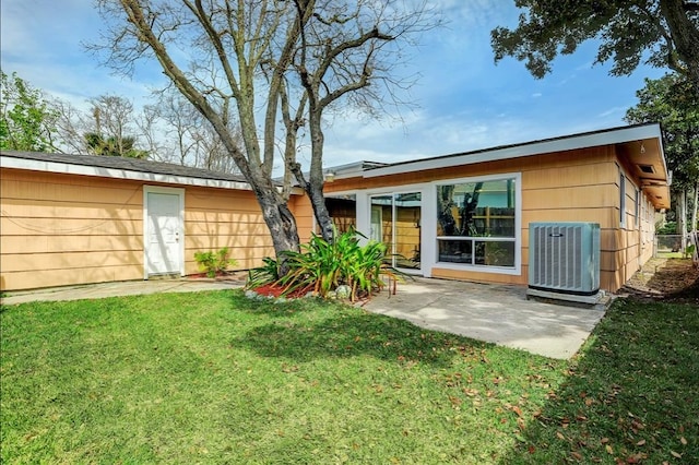 rear view of house featuring a lawn, cooling unit, and a patio