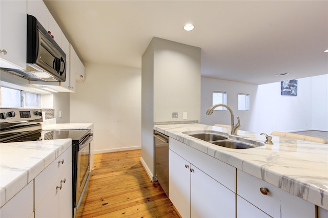 kitchen with sink, stainless steel appliances, white cabinetry, and light hardwood / wood-style flooring