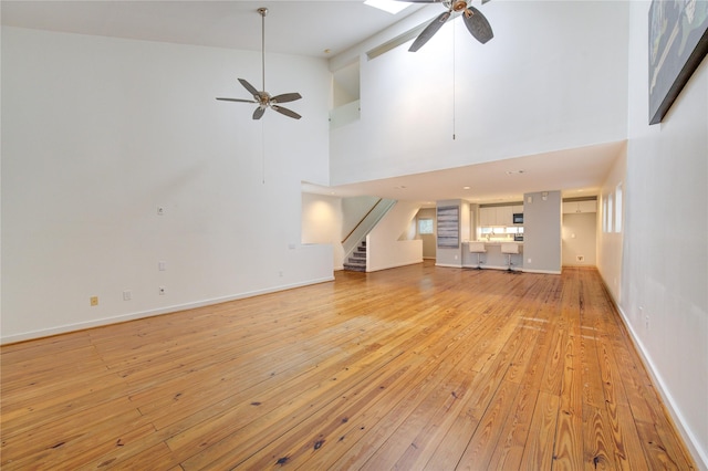 unfurnished living room featuring ceiling fan, light hardwood / wood-style flooring, and high vaulted ceiling