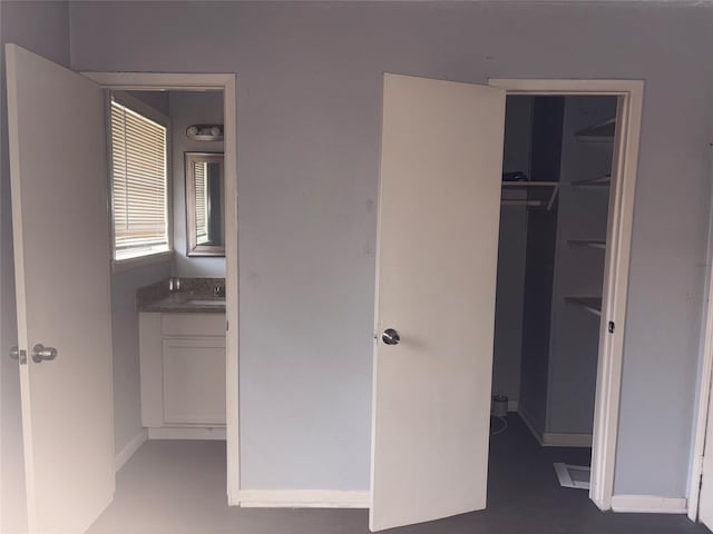 unfurnished bedroom featuring a walk in closet, a closet, and sink