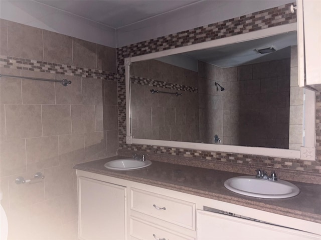 bathroom with vanity, tiled shower, and tasteful backsplash