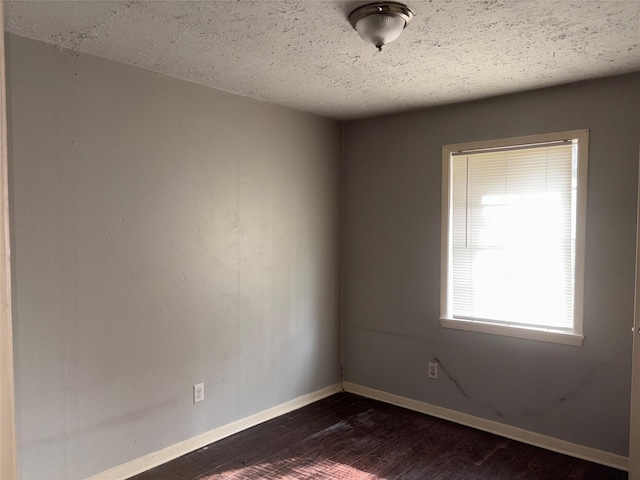 empty room with dark hardwood / wood-style floors and a textured ceiling