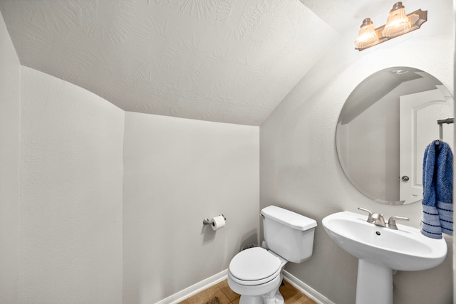 bathroom featuring hardwood / wood-style floors, lofted ceiling, and toilet