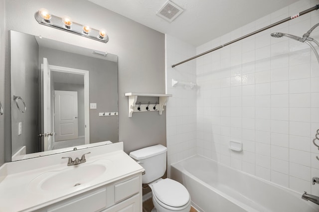 full bathroom with a textured ceiling, vanity, toilet, and tiled shower / bath