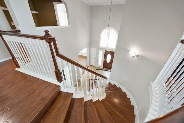 staircase with hardwood / wood-style flooring and a high ceiling