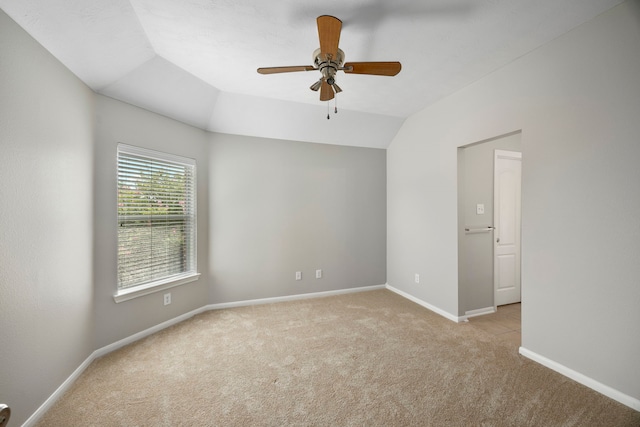 empty room featuring ceiling fan, lofted ceiling, and light carpet