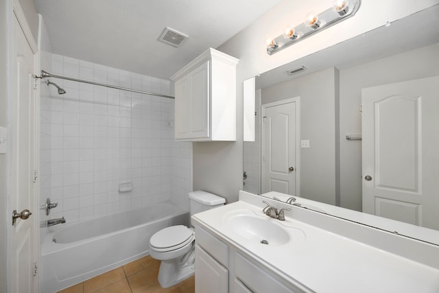 full bathroom featuring tile patterned flooring, vanity, tiled shower / bath combo, and toilet