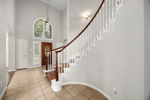 tiled foyer with crown molding and a high ceiling