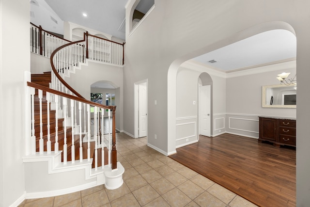 entrance foyer featuring light hardwood / wood-style flooring, an inviting chandelier, a high ceiling, and ornamental molding