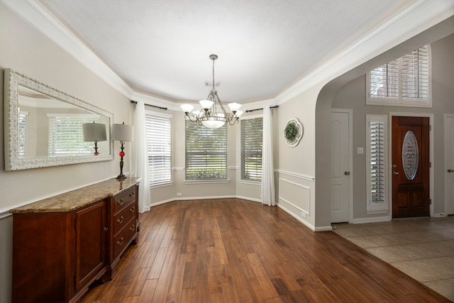 unfurnished dining area with crown molding, dark hardwood / wood-style floors, and a notable chandelier