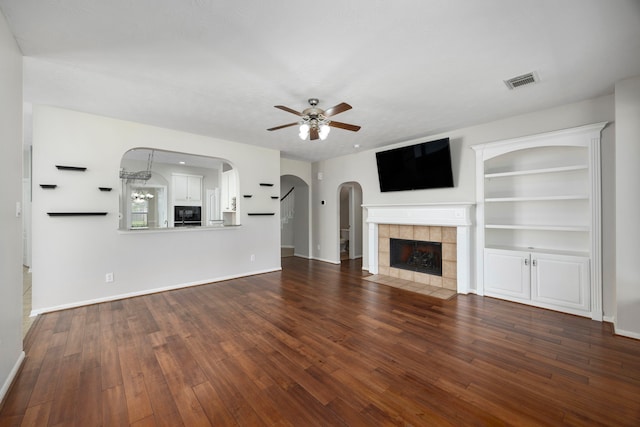 unfurnished living room featuring a fireplace, dark hardwood / wood-style floors, built in features, and ceiling fan