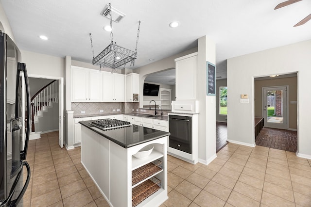 kitchen with refrigerator, stainless steel gas cooktop, ceiling fan, a center island, and white cabinetry