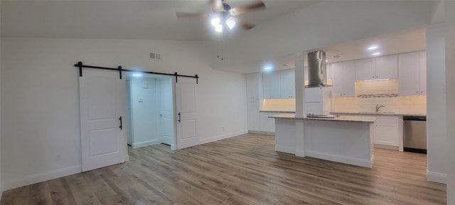 kitchen featuring a barn door, extractor fan, a kitchen island, stainless steel dishwasher, and white cabinets