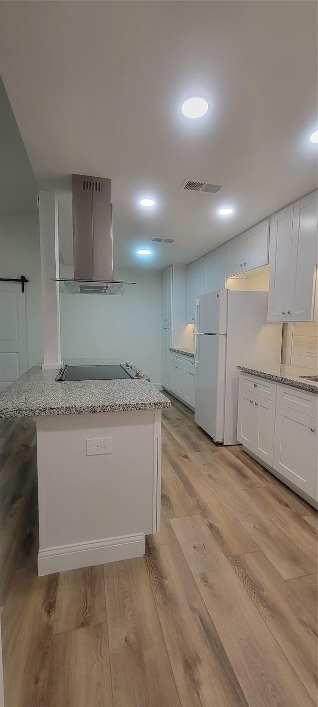 kitchen with light stone countertops, white cabinets, light wood-type flooring, and range hood