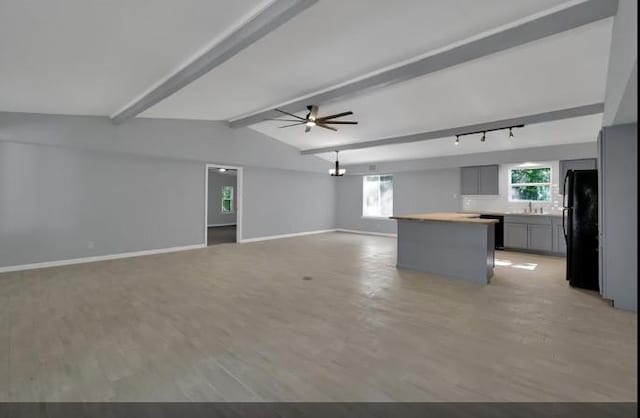 unfurnished living room featuring vaulted ceiling with beams, light hardwood / wood-style floors, ceiling fan, and sink