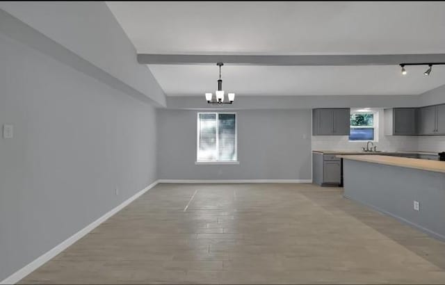 kitchen featuring lofted ceiling with beams, gray cabinets, light hardwood / wood-style flooring, and a healthy amount of sunlight