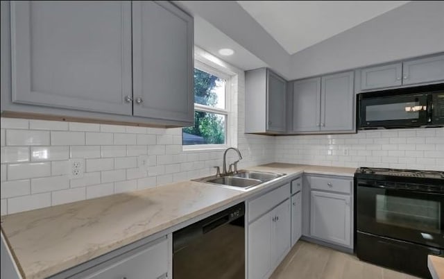 kitchen featuring gray cabinetry, backsplash, black appliances, sink, and vaulted ceiling