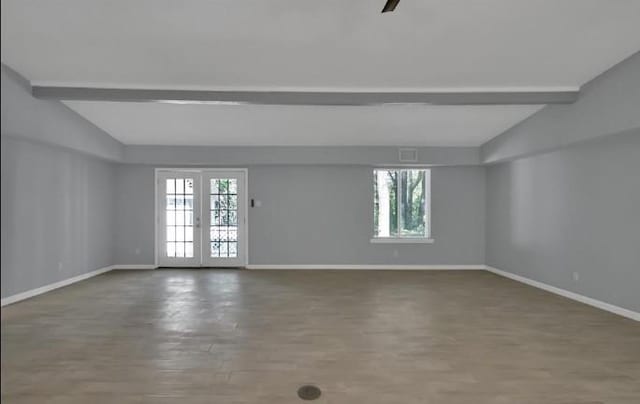 empty room featuring french doors, lofted ceiling with beams, and wood-type flooring