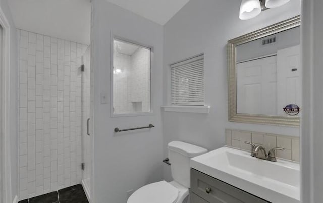 bathroom with tile patterned floors, vanity, toilet, and tiled shower