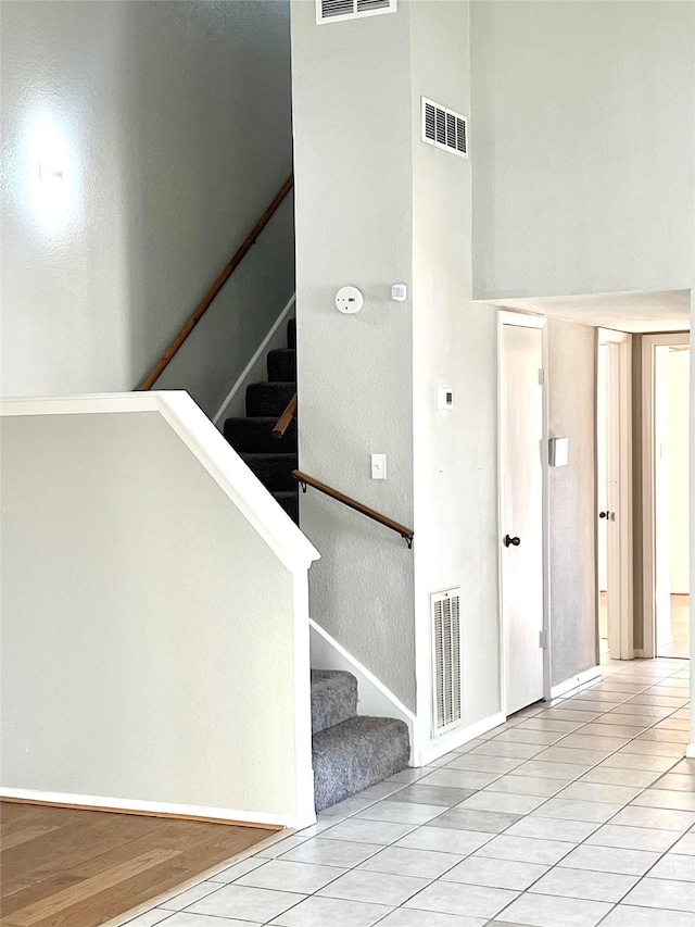 stairway with wood-type flooring and a towering ceiling