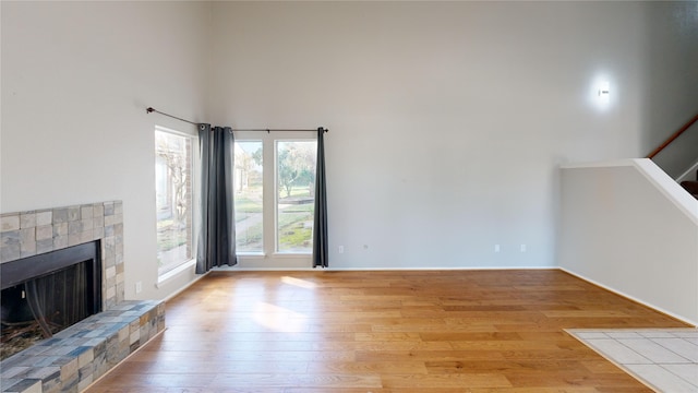 7854 Green Lawn Dr Unit 7854, Houston, TX 77088 - unfurnished living room with hardwood / wood-style floors, a towering ceiling, a fireplace with raised hearth, and stairway