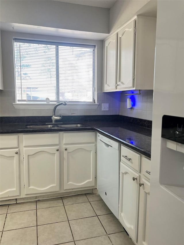 7854 Green Lawn Dr Unit 7854, Houston, TX 77088 - kitchen with white dishwasher, light tile patterned floors, white cabinets, dark countertops, and decorative backsplash