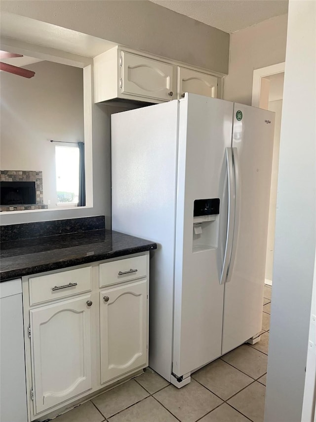 kitchen with white cabinets, light tile patterned floors, white fridge with ice dispenser, and ceiling fan