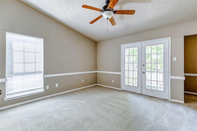 carpeted spare room with ceiling fan, french doors, a textured ceiling, and vaulted ceiling