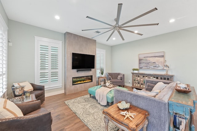 living room with visible vents, recessed lighting, ceiling fan, a tile fireplace, and light wood-type flooring